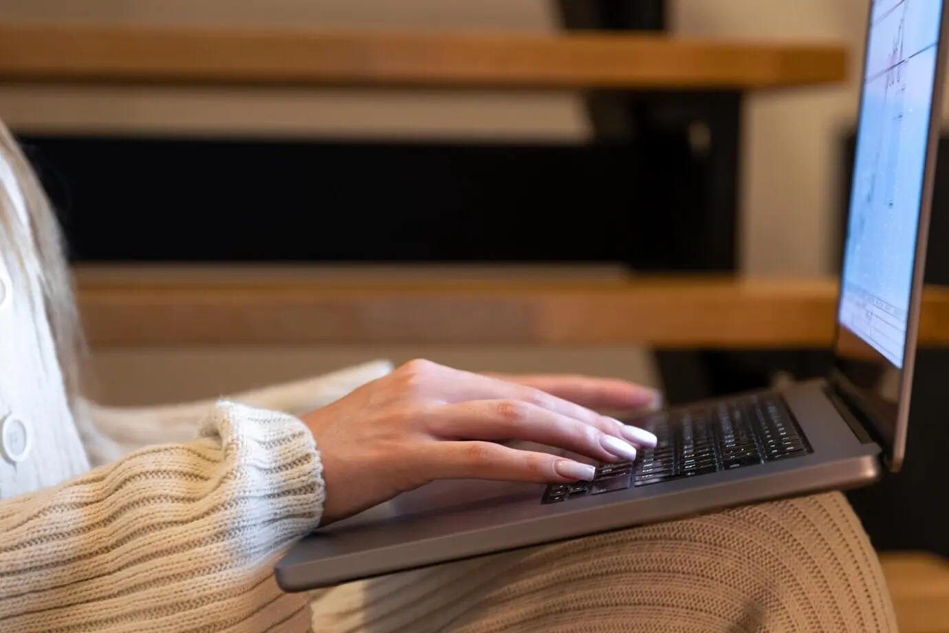 Nahaufnahme von Händen auf der Tastatur, während eine Frau Daten auf einem Laptop analysiert.